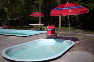a hot tub with an umbrella and a chair next to a pool at Casa Ampla de Praia 2 Piscinas e Ar Condicionado in Matinhos