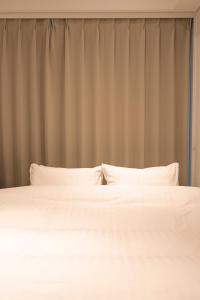 two white beds in a bedroom with a curtain at Cava House - Vacation STAY 07286v in Tokyo