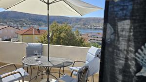 a table and chairs on a balcony with an umbrella at Apartments Burcul Pag in Pag