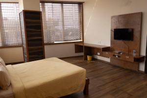 a bedroom with a bed and a tv and windows at Hotel Grand Inn Jamkhandi in Jamkhandi