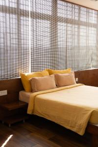 a bed with yellow pillows in a room with windows at Hotel Grand Inn Jamkhandi in Jamkhandi +44 photos