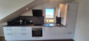 a small kitchen with white cabinets and a window at Neckartalblick in Nürtingen