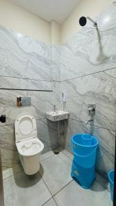 a bathroom with a toilet and a blue trash can at Hotel Shri Kaila Devi in Ujjain
