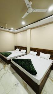 two beds in a room with a ceiling at Hotel Shri Kaila Devi in Ujjain