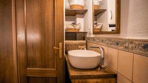 a bathroom with a sink and a wooden door at Casa Rural Pilón Azul in Belerdas
