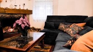 a living room with a black couch and a fireplace at Casa Rural Pilón Azul in Belerdas