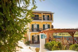 a yellow house with a balcony on the side of it at Potamos Apartments in Sidari