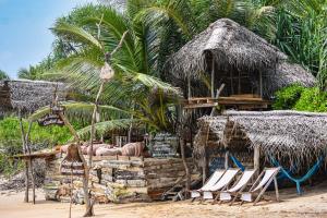 a beach with chairs and a hut with palm trees at Cinnabar Resort in Tangalle