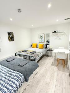 two beds in a room with a table and a desk at Fulham Guest Studios 268 in London
