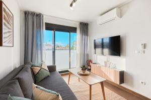a living room with a couch and a tv at Las Dunas 215 - by Welcomely in Oliva