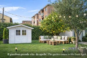 a white shed sitting in a yard next to a tree at The Green Gate - Airport Guest House in Pisa