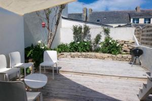 a patio with white chairs and a stone wall at Village du Manémeur in Quiberon +7 photos