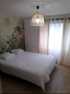 a bedroom with a white bed and a chandelier at Village du Manémeur in Quiberon