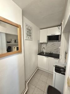 a small kitchen with white cabinets and a sink at A l'orée de Croix - AbsoluteHome in Croix +3 photos