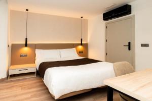a bedroom with a large bed and a table at L'Agora Rooms in Bocairent