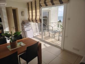 a living room with a dining room table and a balcony at Horizon Bliss at Coral Bay in Peyia