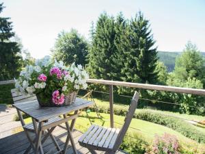 a picnic table with a basket of flowers and a chair at Cottage in the heart of the Ardennes in Waimes