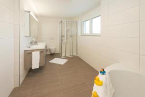 a white bathroom with a tub and a shower at Millegga Grächen in Grächen