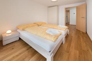 a large white bed in a room with wooden floors at Millegga Grächen in Grächen +2 photos