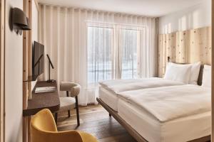 a bedroom with a bed and a desk and a window at The Suites in St. Moritz