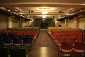 an empty auditorium with red chairs and a stage at Hotel Grand Inn Jamkhandi in Jamkhandi