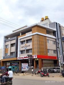 a building with people riding motorcycles in front of it at Hotel Grand Inn Jamkhandi in Jamkhandi