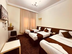 a hotel room with three beds and a window at فندق أوفوك كيندا - ofok kenda hotel in Az Zahrāʼ