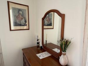 a dressing table with a mirror and a vase of flowers at "The Moment"- rooms Bergamo center, self check-in, late Arrivals in Bergamo
