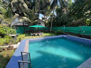 a swimming pool with a table and an umbrella at Beach Side Home Stay - Kihim in Kīhīm +21 photos