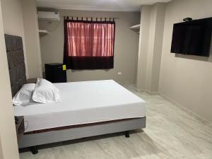 a bedroom with a white bed with a window at Hostal Bellagio in Guayaquil +18 photos