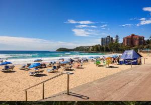 a beach with chairs and umbrellas and the ocean at Captain's Pick at Manly Beach plus Parking in Sydney