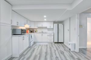 a white kitchen with white cabinets and a refrigerator at A very peaceful home in Oshawa