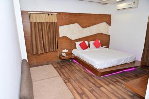 a bedroom with a bed with red pillows at Sri Shivam Hotel in Gondia