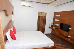 a bedroom with a white bed and a tv at Sri Shivam Hotel in Gondia