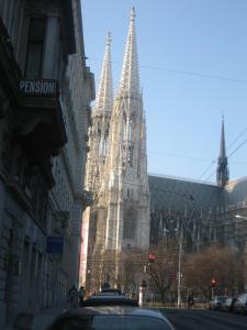eine Kirche mit zwei Türmen auf einer Stadtstraße in der Unterkunft Pension Schottentor in Wien