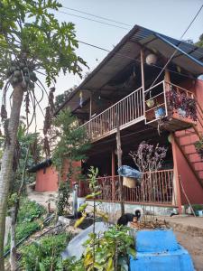 a house with a balcony on the side of it at Nuwakot Hills Farmstay in Trisūli Bāzār