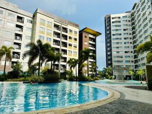 a large swimming pool with palm trees and buildings at Avida Condo Lux Studio Unit in Iloilo City