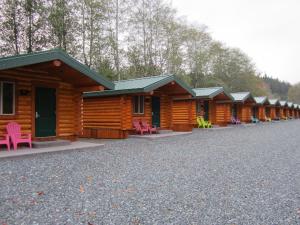 a row of wooden cabins with pink chairs in front at Port Hardy Cabins in Port Hardy