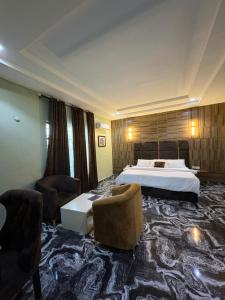 a hotel room with a bed and two chairs at Ja'oak Hotel and Suite in Mama
