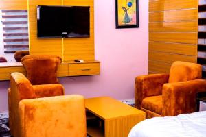 a room with chairs and a tv and a bed at Ja'oak Hotel and Suite in Mama +3 photos