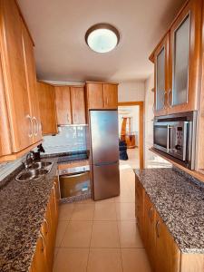 a kitchen with wooden cabinets and a stainless steel refrigerator at Apartamento PLAYANALA in Torrox Costa