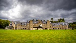 a large building on a grassy field under a cloudy sky at Loch Tummel Hotel in Tummel Bridge
