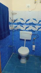 a bathroom with a toilet and a blue wall with dolphins at Apple Zone Home stay in Banjār