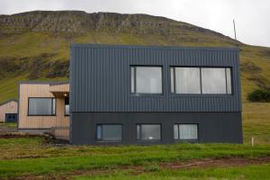 a black house with a hill in the background at Eyri Farm in Kjósahreppur