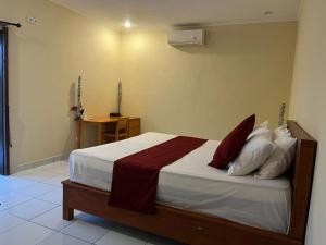 a bedroom with a bed with red and white pillows at Dewenten Home Stay With View Mount Agung in Tulamben