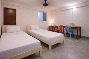 a room with two beds and a table and a desk at Mahadev Guest House in Deoghar