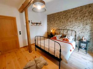 a bedroom with a bed and a stone wall at Grand gîte champêtre ! LA SOURCE DE NOS RACINES - CORPS DE FERME AU COEUR DU PARC NATUREL DE L'AVESNOIS in Beaufort