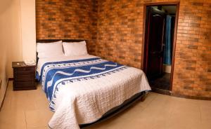 a bed in a room with a brick wall at Hospedaje la Cascada in Riobamba