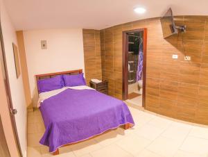 a bedroom with a purple bed and a shower at Hospedaje la Cascada in Riobamba