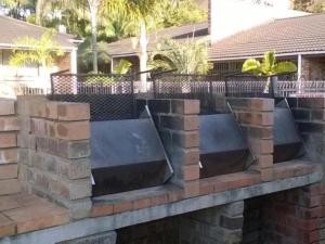 a retaining wall with stone blocks and a fence at Flamboyant Apartments in St Lucia